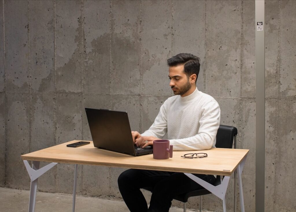 A man sitting at a desk, working on a laptop, focused on integrating business systems and ensuring compatibility.